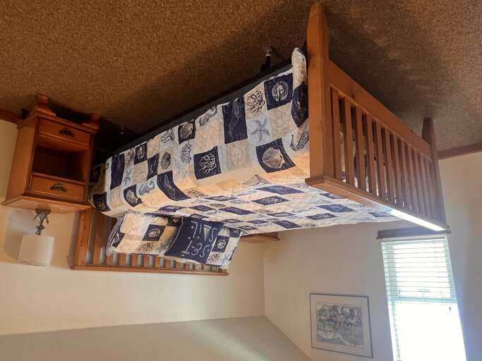 Your cozy space features a creative bunk bed setup with nautical-themed bedding and warm wood furnishings.