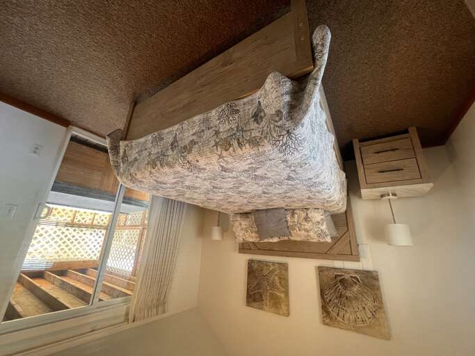 Drift off beneath this stunning carved wooden canopy bed, where intricate maritime details and cozy linens create your perfect seaside sanctuary.