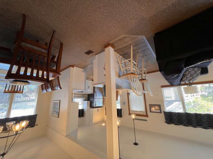 Experience this remarkable upside-down living space where chairs defy gravity on the ceiling while you relax below in this uniquely playful retreat.