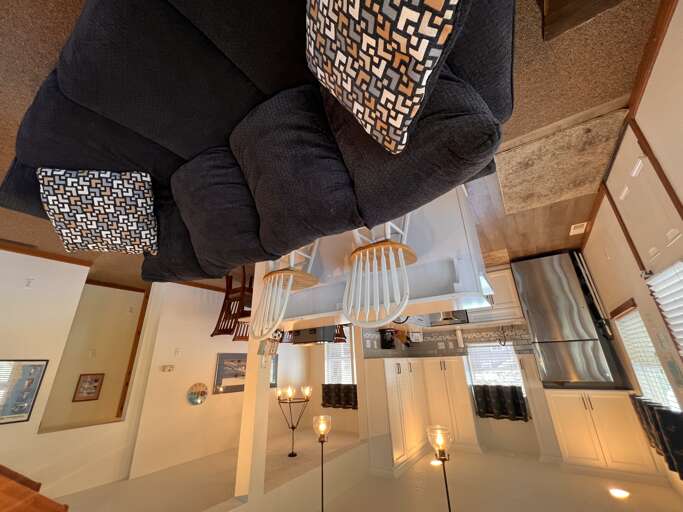 Relax in this stylish loft space where contemporary comfort meets modern design, featuring a cozy sectional and sleek kitchen below.