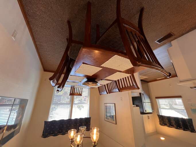 Relax in your unique loft space featuring creative upside-down table seating and warm wooden accents throughout.