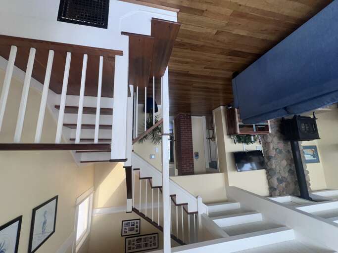 Your cozy living space features exposed wood beams, a charming fireplace, and open stairs creating rustic warmth.