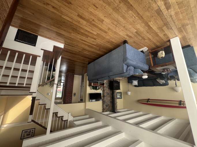 Relax in your cozy living room featuring a blue sectional sofa, warm wood-beamed ceiling, and charming rustic touches.