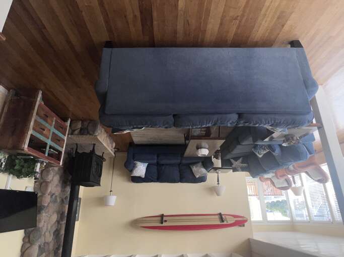 Relax in your cozy living space with plush blue seating, warm wood beams, and charming rustic stone fireplace creating the perfect retreat.