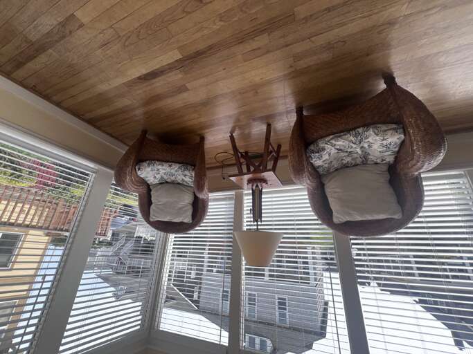 Sink into cozy wicker chairs in your bright sunroom, where natural light streams through blinds and wood ceiling adds warmth.