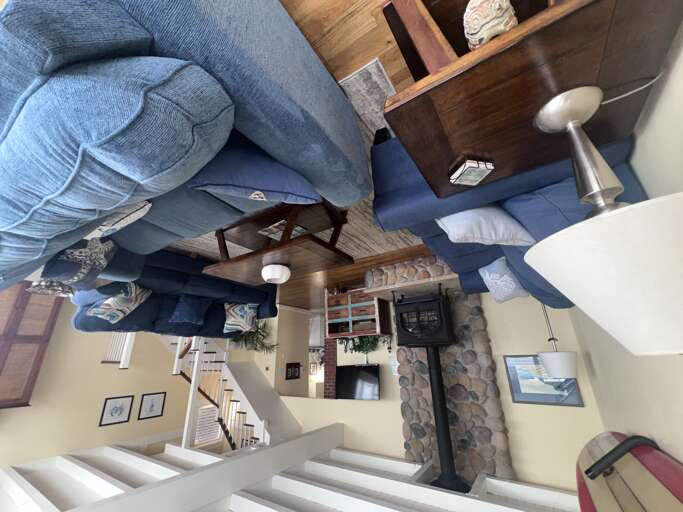 Sink into plush blue sofas around your rustic fireplace, where weathered wood beams meet stone - your perfect retreat for cozy evenings.