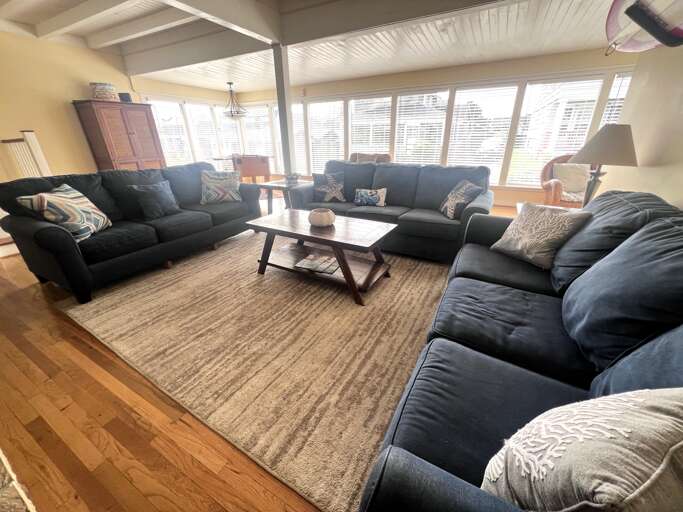 Sink into plush sectional seating in your spacious living room, where natural light floods through panoramic windows and warm hardwood floors invite barefoot comfort.