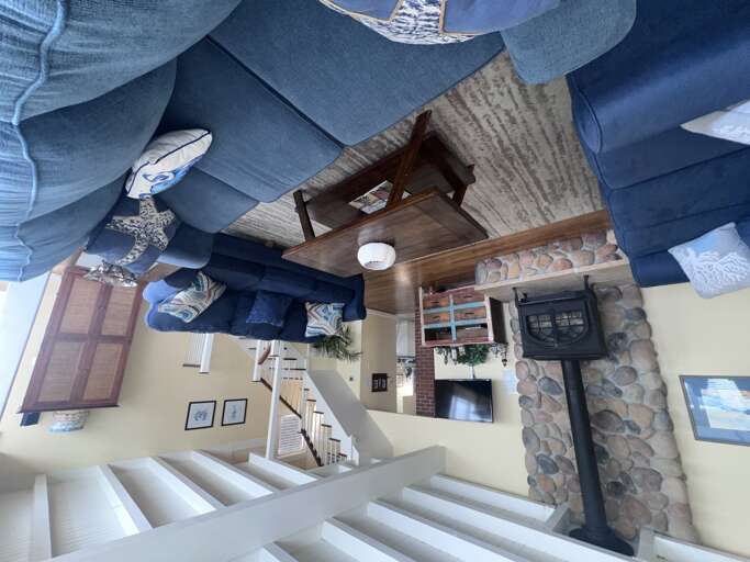 Your spacious living room welcomes you with plush blue seating, rustic exposed beams, and a stunning stone fireplace creating the perfect gathering spot.