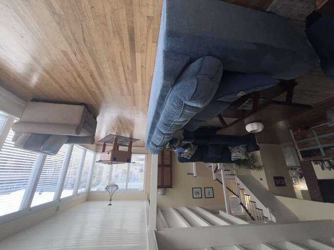 Your spacious open-plan living area features soaring wood-beamed ceilings, comfortable seating, and abundant natural light streaming through large windows.