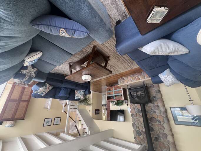 Unwind in your spacious living room with plush blue seating, rustic stone fireplace, and open layout connecting to the kitchen.