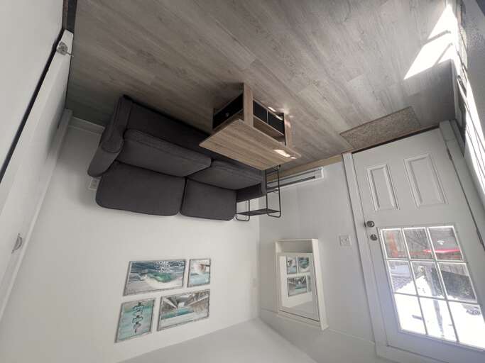 Your cozy loft bedroom features a comfortable sofa, natural light streaming through bright windows, and unique coastal artwork adorning crisp white walls.