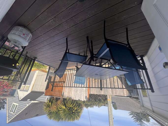 This covered porch offers a welcoming outdoor dining spot with stylish seating and a cozy ambiance, perfect for enjoying meals or morning coffee in the fresh air.