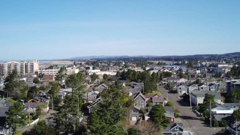 An elevated view of the coastal neighborhood surrounding the property, with residential streets and distant ocean vistas framing this scenic coastal community.