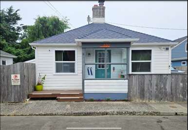 A charming coastal cottage with a welcoming teal door, wooden deck, and peaceful residential setting provides the perfect home base for your getaway.