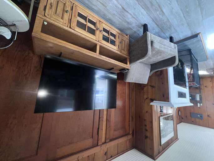 Your cozy living space features rich wood furnishings, a mounted flat-screen TV, and thoughtful storage in warm, rustic tones that make you feel right at home.
