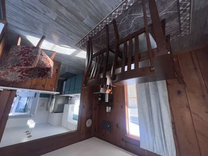 Your cozy loft retreat features rich wood details and a charming staircase leading to your private sleeping space, with natural light streaming through the windows to brighten your home away from home.