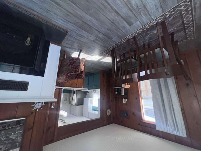 Your rustic hideaway features rich wood paneling, a cozy sleeping loft accessible by ladder, and a compact kitchenetteâperfect for a memorable mountain getaway.
