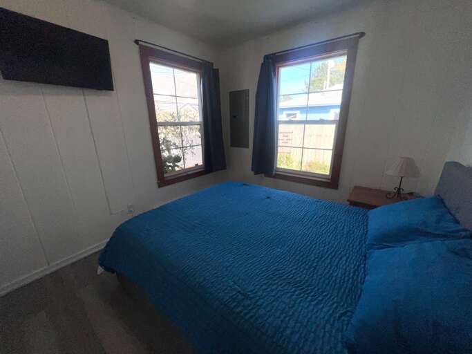 Wake up in this bright, cozy bedroom where twin windows frame cheerful garden views. Your plush bed awaits, promising restful nights.