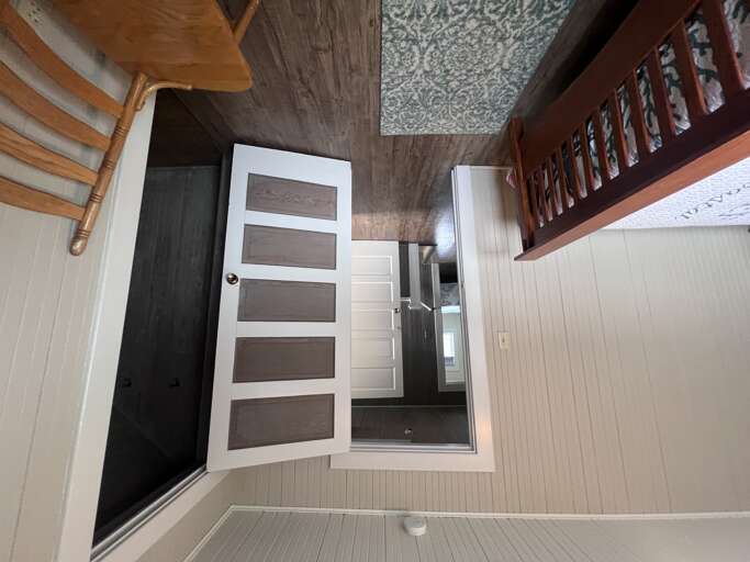 Stylishly designed interior and Classic wood-look floors. Features a loft sleeping area accessed by stairs, clean white paneling, and contemporary doors blending rustic charm with urban sophistication.