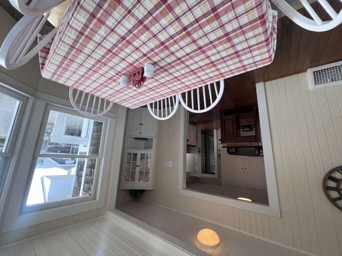 Bright, cheerfully designed kitchen with white-painted wood walls and playful plaid ceiling. Natural light floods through generous windows, making meal prep a joy.