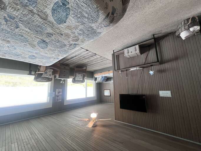 Relax in your spacious retreat featuring natural wood tones, a unique canopy-style sleeping nook, and large windows that flood the space with light. Coastal decor and ceiling fan complete this breezy getaway.