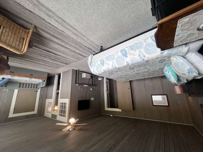 Your spacious open bedroom blends coastal charm with modern convenience, featuring a cozy ceiling fan, soothing sea-inspired linens, and a tranquil flow between sleeping and living spaces.