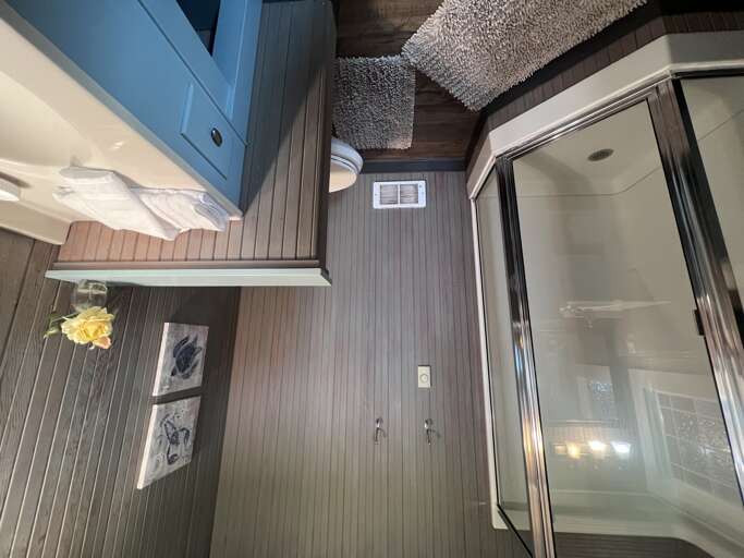Your stylish bathroom features blue coastal-inspired cabinetry, a glass-enclosed walk-in shower, and plush soft towels waiting for you after a warm rinse.