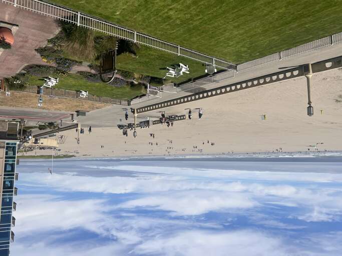 Aerial view of a beachfront property with direct sand access, landscaped grounds, and inviting outdoor amenities along the shoreline.