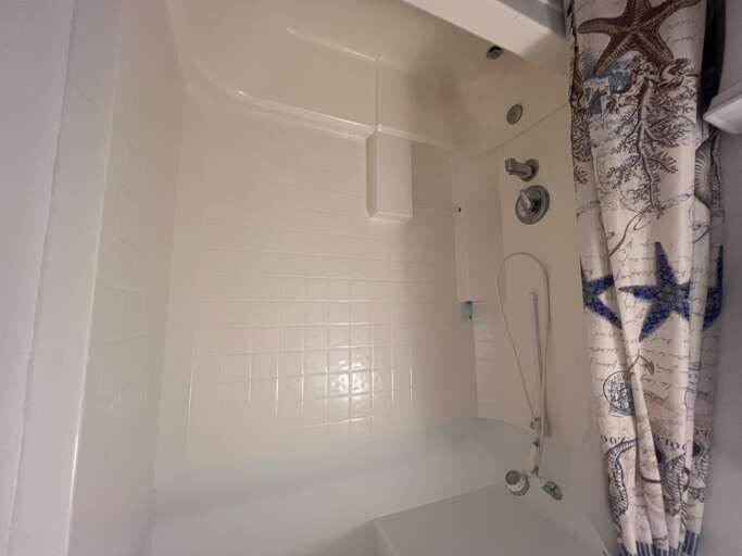 Unwind in your pristine tub with coastal décor, where gleaming white tile and nautical touches set the tone for a relaxing soak after exploring the area.
