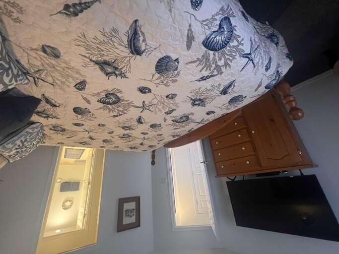 Drift off under an enchanting canopy of seashells and ocean creatures, lovingly illustrated on your ceiling. Warm wooden furniture and soft lighting create a serene coastal retreat for your stay.