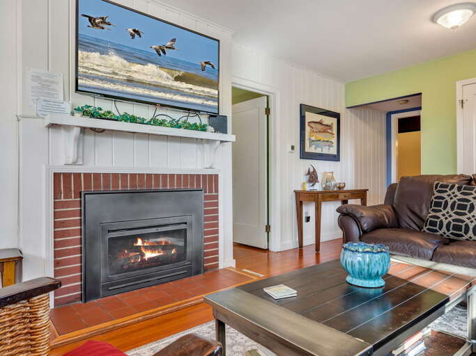 Curl up in your cozy living room where the warm glow of the fireplace invites you to relax after a day of coastal adventures. Sink into the plush leather sofa and unwind in this charming, welcoming space.