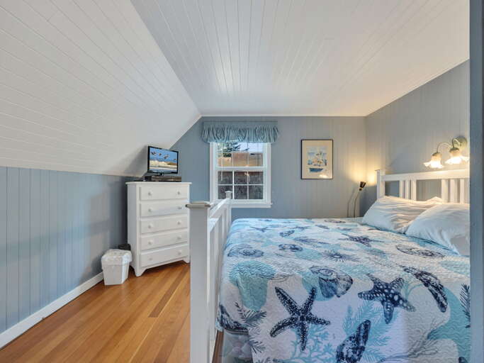 Drift off beneath coastal-inspired bedding in this serene loft bedroom, where vaulted ceilings and soft blue tones create your peaceful seaside retreat.