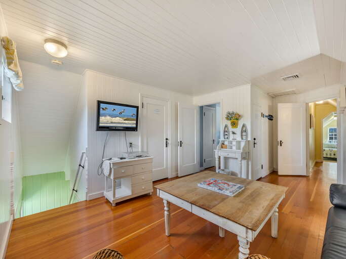 Step into your bright coastal retreat with warm wood floors, charming white shiplap walls, and a welcoming living space perfect for unwinding after a day of seaside adventures.
