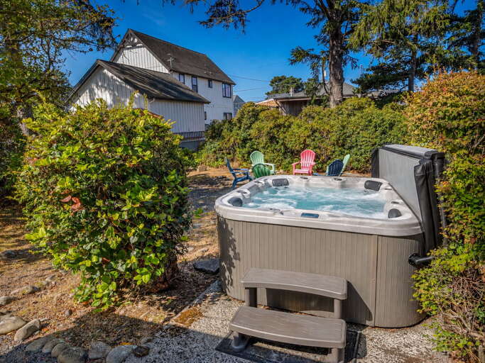 Soak away your cares in your private hot tub, nestled among lush greenery with colorful Adirondack chairs nearby for lounging under the sun.