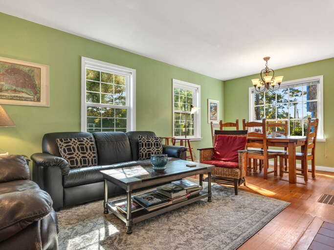 Settle into your welcoming living and dining space where sunlight streams through large windows, inviting you to relax on the plush leather sofa or gather around the warm wooden dining table for memorable meals together.