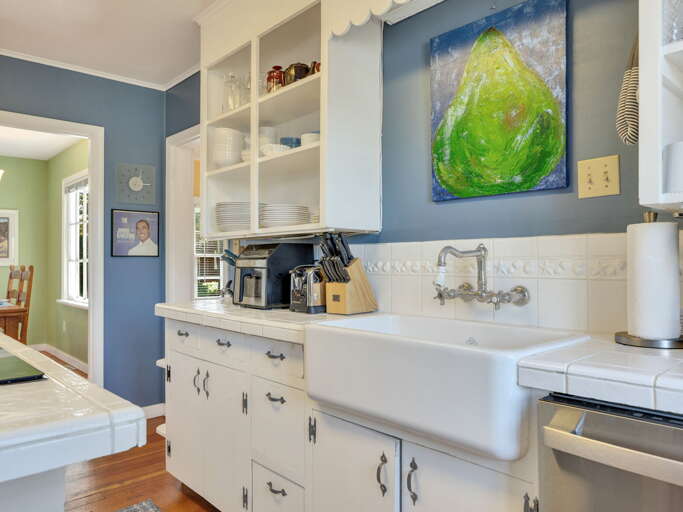 Charming farmhouse kitchen with classic sink, white cabinetry, and vintage-inspired backsplash. Open shelving and thoughtful details make cooking a pleasure.