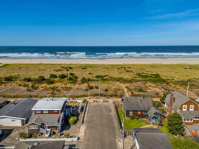 A coastal property nestled between residential neighborhoods and pristine beachfront, with rolling waves and expansive sandy shores just steps away from the accommodation.