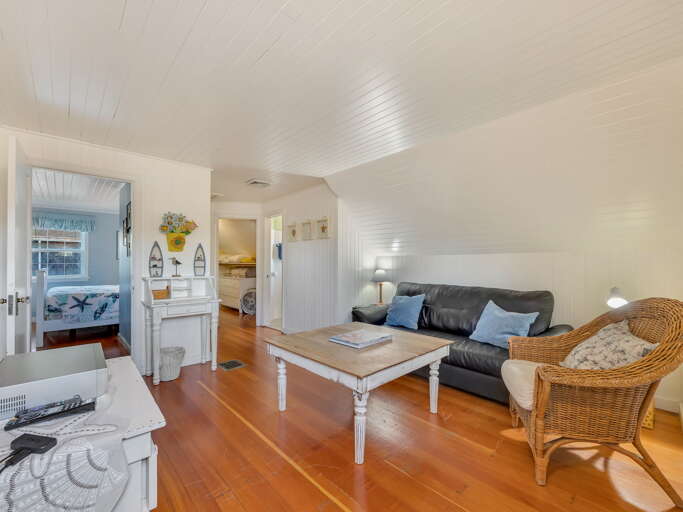 Settle into your cozy upstairs retreat with warm wood floors and charming sloped ceilings. The living space flows seamlessly into a restful bedroom, perfect for unwinding after beach adventures.