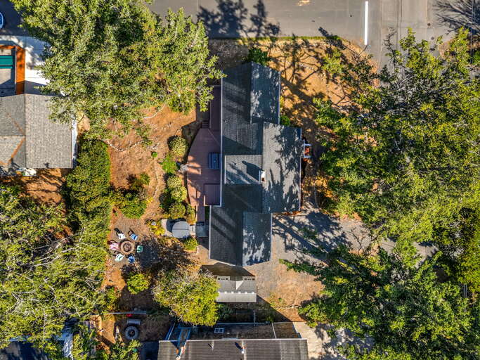 Aerial view of the property nestled in a quiet residential neighborhood, surrounded by mature trees and ample outdoor space.