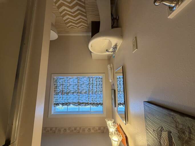 Your private bathroom features a modern vanity with fresh towels and a bright window that fills the space with natural light, creating a clean and welcoming retreat.