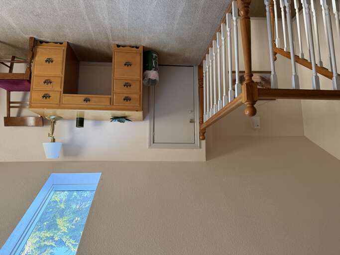 Your cozy loft retreat features warm wood furnishings and a skylight framing treetops above. Climb the charming staircase to your private sleeping nook under sloped ceilings—a peaceful haven bathed in natural light.
