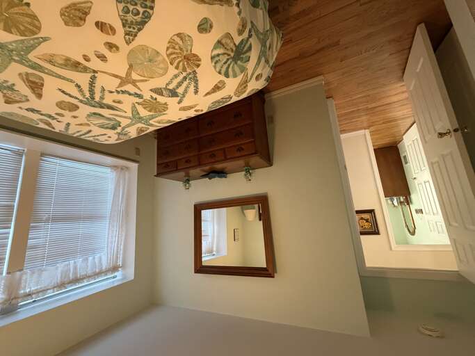 Your charming bedroom retreat features warm wood cabinetry, natural light, and a cheerful botanical ceiling mural that brings the outdoors in.