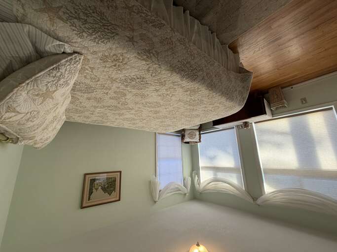 Sink into plush, textured bedding in your serene retreat, where natural light filters through while warm wood ceilings add cozy charm overhead.
