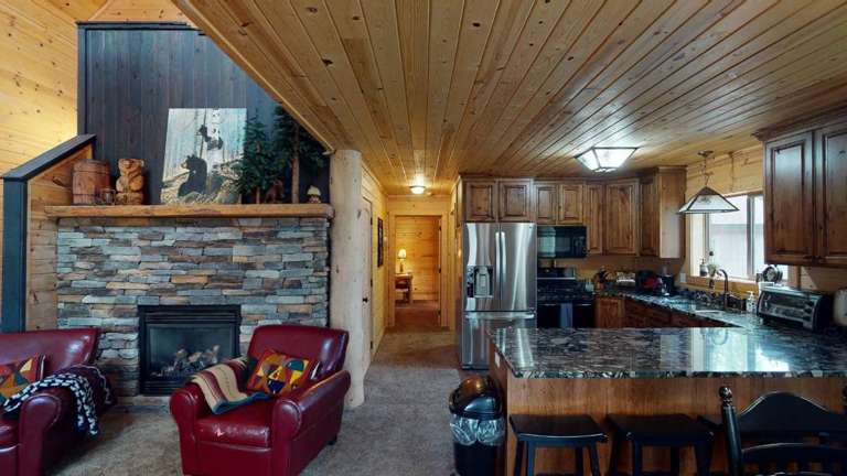 Interior View Of A Living Room With Kitchen, Fireplace, And Wooden Ceiling