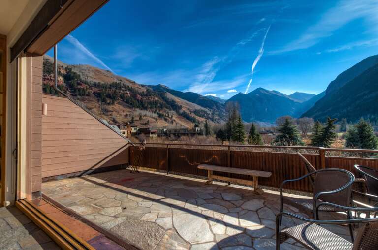 The balcony of this Colorado Mountain vacation rental, with chairs and a small bench.