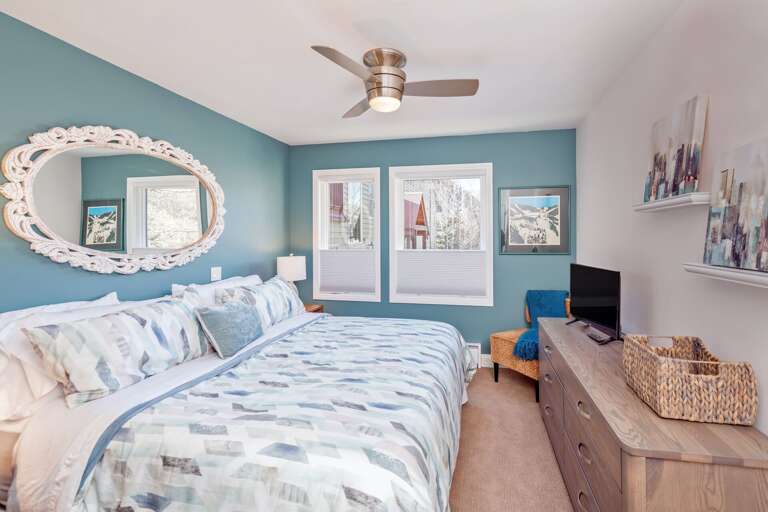Bedroom with Large Bed, Ceiling Fan, Drawer Dresser, TV, and Chair