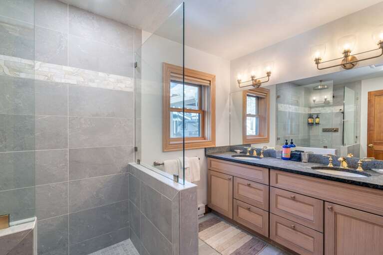 Bright Bathroom In Vacation Rental With Mirrored Vanity And Glass Shower