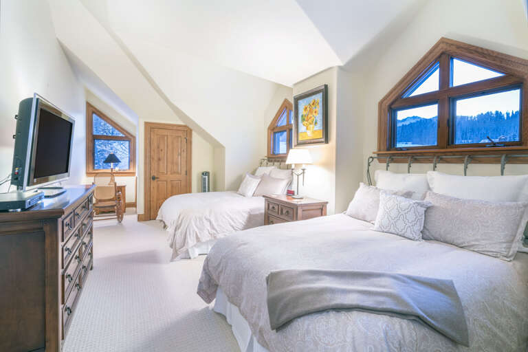 Another one of the bedrooms, complete with two large beds, a nightstand in between, and a wall-mounted TV above a dresser. Another one of the bedrooms, complete with two large beds, a nightstand in between, and a wall-mounted TV above a dresser.