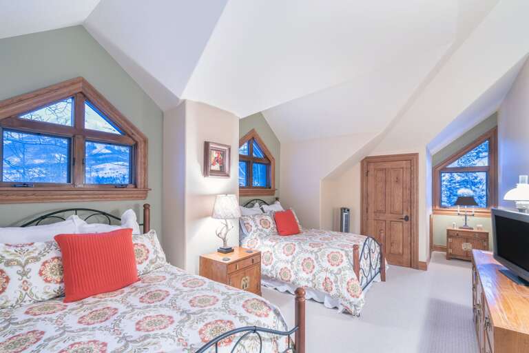 Two beds separated by a nightstand, with a TV and dresser at the foot of them. Two beds separated by a nightstand, with a TV and dresser at the foot of them.