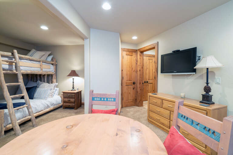 Large bedroom with table and seating, a bunk bed, and wall-mounted TV above a dresser. Large bedroom with table and seating, a bunk bed, and wall-mounted TV above a dresser.